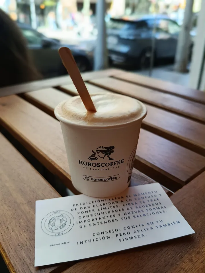 Un café de HOROSCOFFEE junto a la tarjeta con la predicción y el consejo del mes
